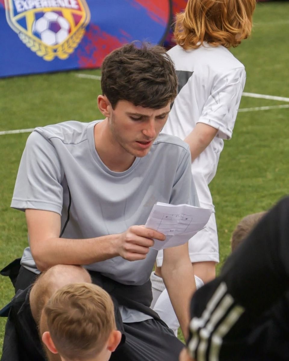 Byron looking over a coaching plan with young players around him