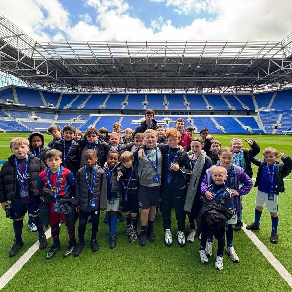 A large group of young players together on the pitch at a stadium
